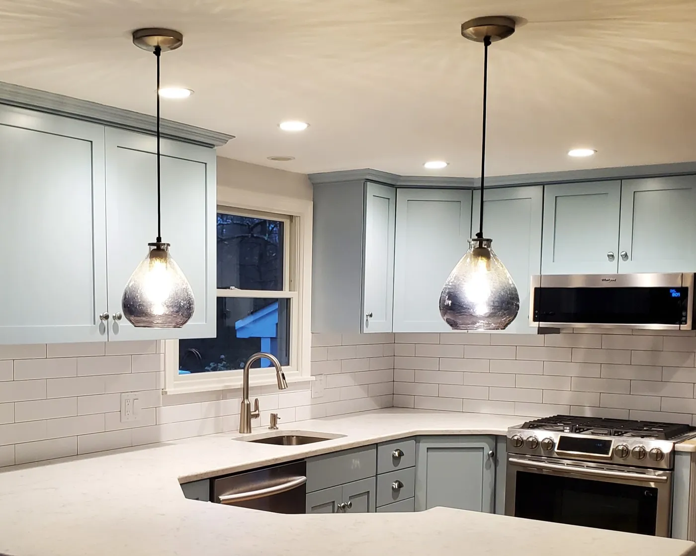Finished kitchen with pendant lights and sage cabinetry