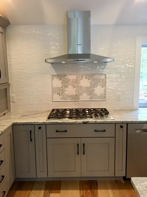 Gray shaker cabinets with range hood and tile backsplash